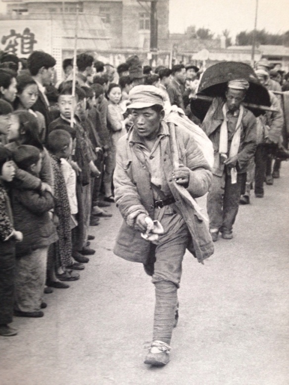 The first soldiers arriving in Nanking on foot.  They are cheered, but at the same time regarded with good deal of anxious curiosity.  In China, a soldier has always been considered a looter, living off the country, for which reason the military profession is greatly despised.